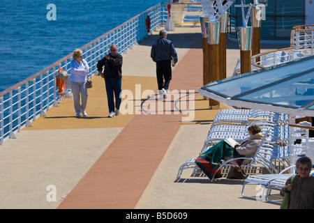 I passeggeri di crociera bundle fino a tenere in caldo durante la camminata e la lettura di libro sulla nave diretta a Alaska da Seattle, WA Foto Stock