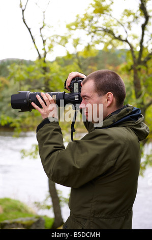 Fotografo utilizzando un D300 con Nikon 70-200mm VR lente fuori dal fiume di Scozia UK Foto Stock