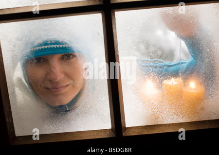 Austria, Salzburger Land, giovane donna guardando attraverso la finestrella, candele accese Foto Stock
