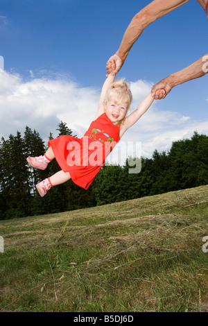 La bionda bambina essendo ruotata intorno, 2 anni, esterno Foto Stock