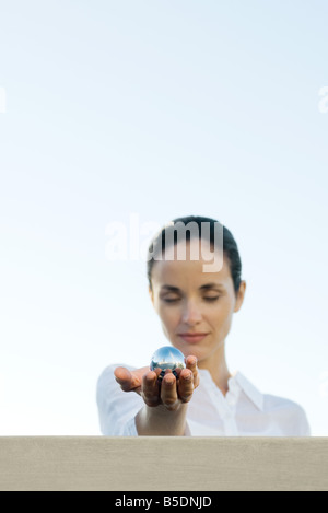 Donna che mantiene la sfera di metallo a occhi chiusi Foto Stock