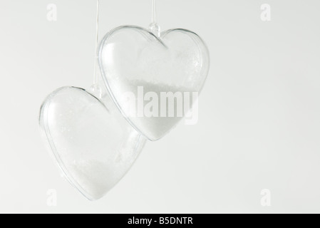 Coppia di cuore a forma di ornamenti di vetro parzialmente riempita con la neve Foto Stock