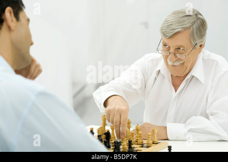 Padre giocando a scacchi con figlio adulto, smirking Foto Stock