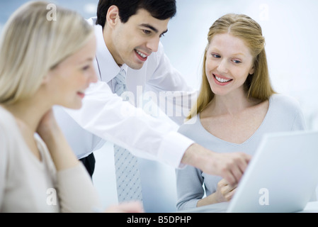 Professional uomo cercando su femmina collega la spalla, puntando al computer portatile Foto Stock