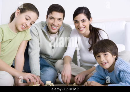 La famiglia gioca domino insieme sorridente Foto Stock