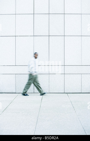 Uomo che cammina con le sue mani in tasca giù il marciapiede Foto Stock