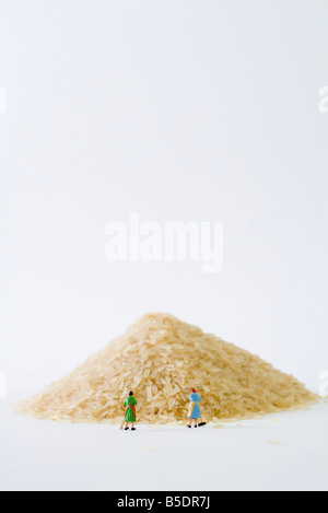 Donne in miniatura spazzando gran mucchio di riso Foto Stock