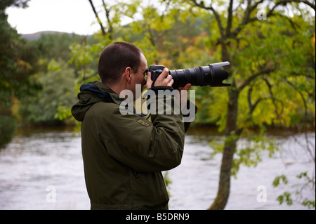 Fotografo utilizzando un D300 con Nikon 70-200mm VR lente fuori dal fiume di Scozia UK Foto Stock