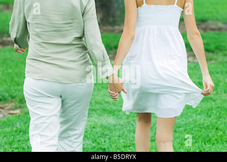 Madre e figlia passeggiate all'aperto, tenendo le mani, ritagliato vista posteriore Foto Stock