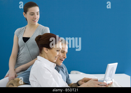 Famiglia seduta sul lettino, guardando il lettore DVD portatile insieme Foto Stock