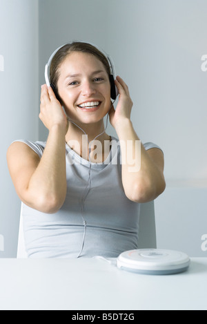 Donna ascolto di un lettore CD portatile, sorridente in telecamera Foto Stock