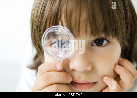 Little Boy guardando attraverso la lente di ingrandimento in telecamera Foto Stock