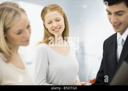 Tre professionisti alla ricerca nella cartella insieme, concentrarsi sulla donna sorridente nel centro Foto Stock