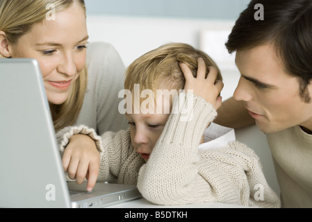 I genitori aiutando little boy utilizzare computer portatili, close-up Foto Stock