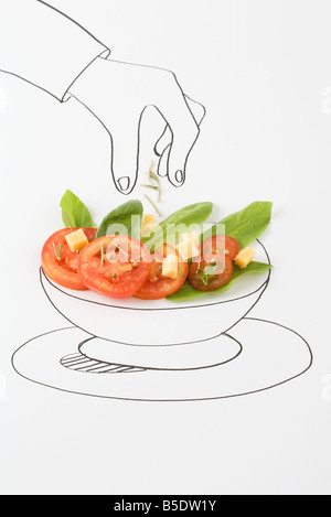 Disegno di mano spolverata condimenti su insalata Foto Stock