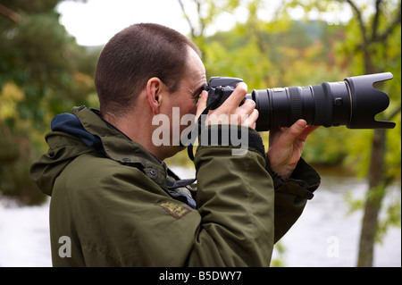 Fotografo utilizzando un D300 con Nikon 70-200mm VR lente fuori dal fiume di Scozia UK Foto Stock