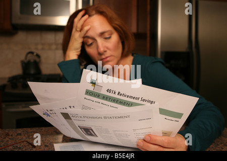 Una donna viene afferrata con preoccupazione e ansia come si guarda oltre il suo investimento dichiarazioni. Foto Stock