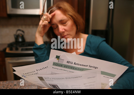 Una donna viene afferrata con preoccupazione e ansia come si guarda oltre il suo investimento dichiarazioni. Foto Stock