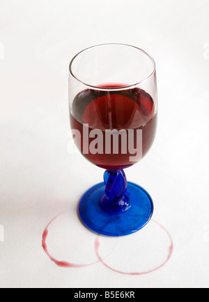 Un bicchiere di vino con macchie di vino anelli sul tavolo bianco diffuso. Foto Stock