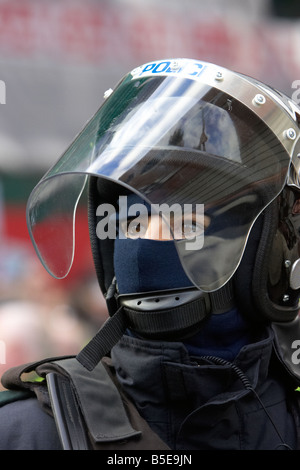 PSNI Servizio di Polizia dell'Irlanda del Nord femmina funzionario di polizia antisommossa che indossa il casco e visiera a guardare Foto Stock
