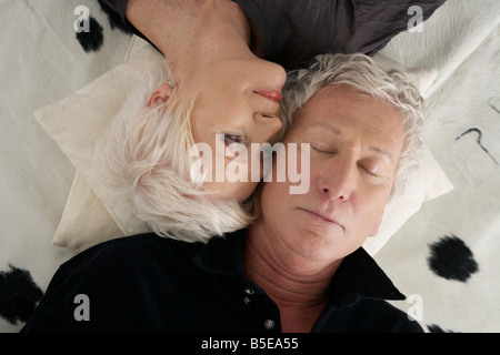 Coppia senior giacente un testa a testa su un cowskin Foto Stock