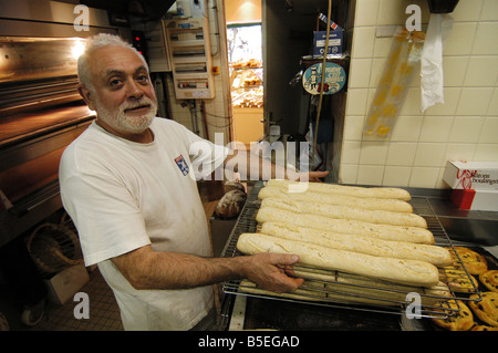 Un cuoco francese al lavoro nel suo panificio assumendo baguette (tipico pane francese ticks) fuori del suo forno. Foto scattata a Nogent, Francia Foto Stock