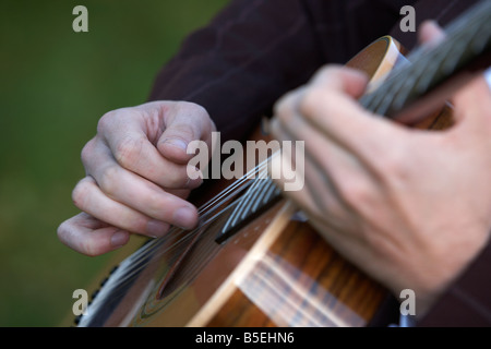 20s mans mani a suonare la chitarra all'esterno delle stringhe di spennatura Foto Stock