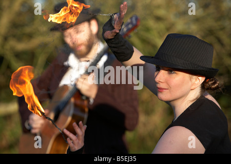 Uomo a suonare la chitarra con donna firepoise fire dancer giocando con il fuoco Foto Stock