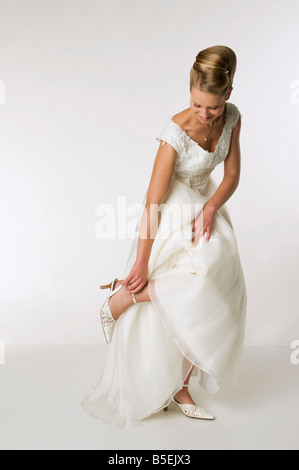 Giovane sposa guardando giù, mano alla caviglia Foto Stock