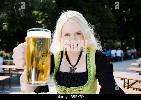 In Germania, in Baviera, Monaco di Baviera, Giardino Inglese, giovane donna tenendo la birra stein, sorridente, ritratto Foto Stock