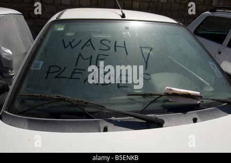 Un lavaggio mi prega di iscrizione motivo scritto sul lurido windowscreen di una macchina sporca Foto Stock