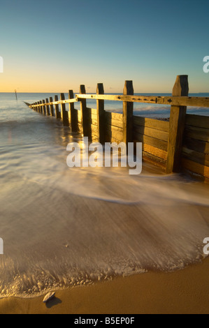 Le onde impetuose intorno al legno le difese del mare sul lungomare di Dawlish all'alba Dawlish Devon Regno Unito Foto Stock