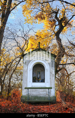 Piccola vecchia cappella tra alberi d'autunno nella luce del sole al tramonto. Il parco del castello di Kačina vicino a Kutná Hora, Repubblica Ceca. Foto Stock