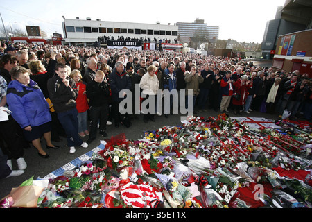 Tifosi si riuniscono al di fuori di Old Trafford per il monaco di baviera disastro aereo memorial cinquantesimo anniversario di fronte all'orologio fermo al momento del crash Foto Stock