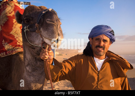 Abdullah, il giro sul cammello uomo su Tamraght beach, Marocco Foto Stock