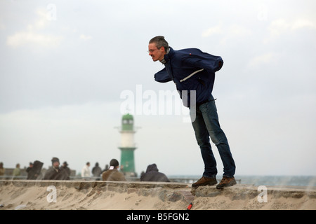 Uomo appoggiato contro il vento tempestoso su una scogliera occidentale, Warnemuende, Germania Foto Stock