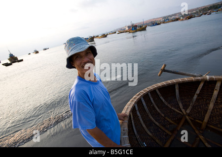 I pescatori sulla spiaggia di Mui Ne coracles tessuti sono le imbarcazioni tradizionali utilizzate nella zona del Vietnam Foto Stock