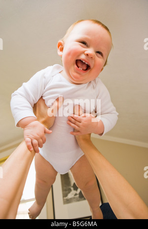 A dieci mesi di old baby boy essendo mantenuto aloft da sua madre Foto Stock