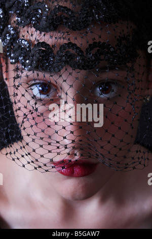 Foto di stock di una giovane donna attraente indossando un velo nero. Indossa profondo rosso rossetto e sta guardando la telecamera. Foto Stock