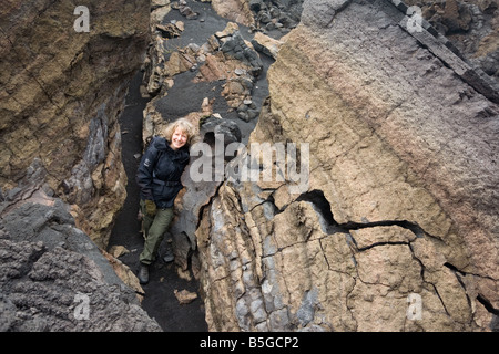 Donna in piedi in un grande crack di congelati di roccia lavica del 1991-1993 eruzione del Mt. Il vulcano Etna, in Valle del Bove Foto Stock