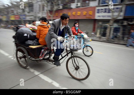 Un pedicap e uno scooter sulla strada, Shanghai, Cina Foto Stock