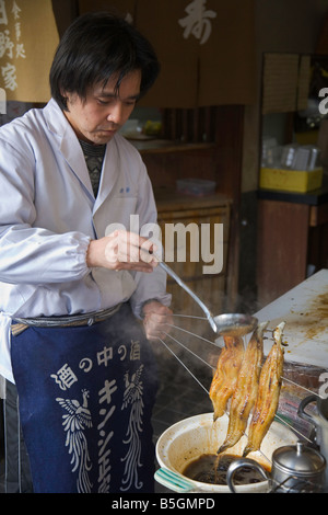 La città di Kyoto Giappone Shop quartiere vicino tempio di Kiyomizu marciapiede ristorante uomo inumidendo di grigliate di pesce Foto Stock