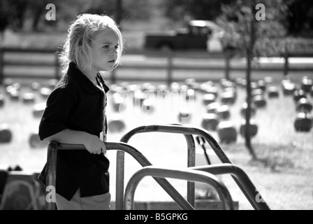 Immagine in bianco e nero di una ragazza su un merry-go-round di un parco giochi per bambini Foto Stock