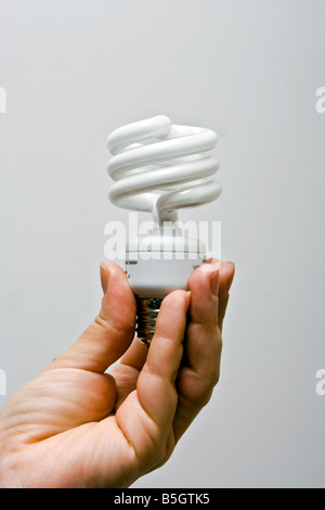 Una mano femmina presentando un ecologici e di risparmio energetico luce fluorescente lampadina Foto Stock