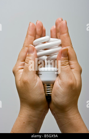 Due mani femminili presentando un ecologici e di risparmio energetico luce fluorescente lampadina Foto Stock