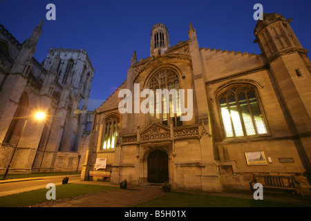 Città di York, Inghilterra. Vista notturna di St Michael le Belfrey chiesa in Minster cantiere, con York Minster in background. Foto Stock