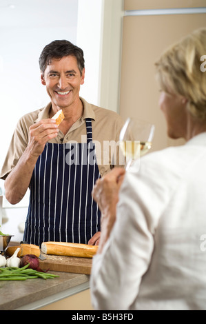 Uomo maturo mangiare baguette, donna di bere un bicchiere di vino bianco Foto Stock