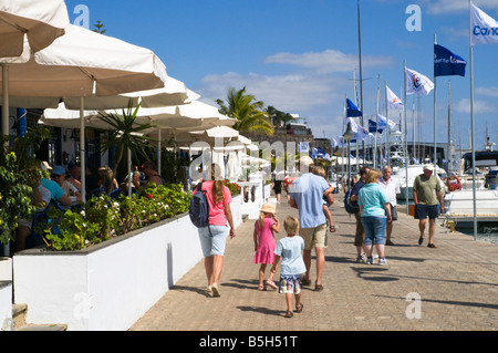 Dh Marina PUERTO CALERO LANZAROTE Tourist vacanzieri famiglia sulla marina prom a piedi passato cafè holiday Foto Stock