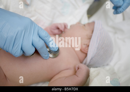 Un neonato che ascolta il cuore di un neonato con uno stetoscopio in ospedale. Foto Stock