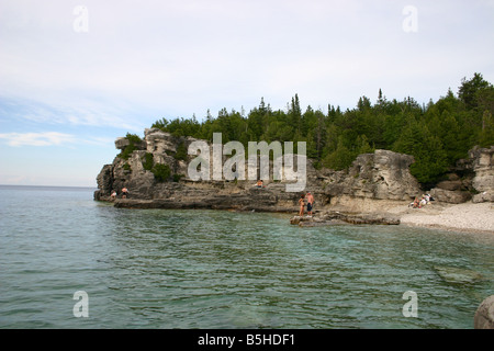 Nuotatori giocare sulle aspre rocce e pietra bianca spiaggia di una isolata insenatura circondata da scogliere. Beuce National Park, Canada. Foto Stock